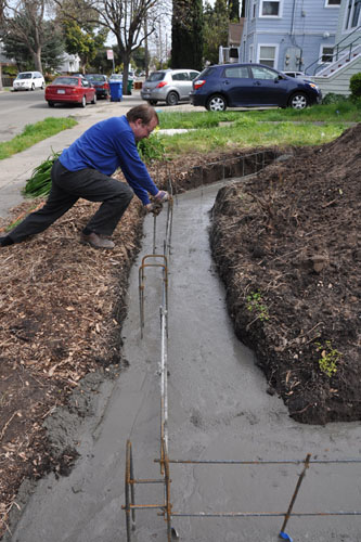 Noel pushes the rebar into place